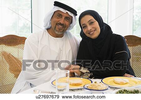 Stock Photo - Couple sitting at dinner table smiling (high key). Fotosearch
