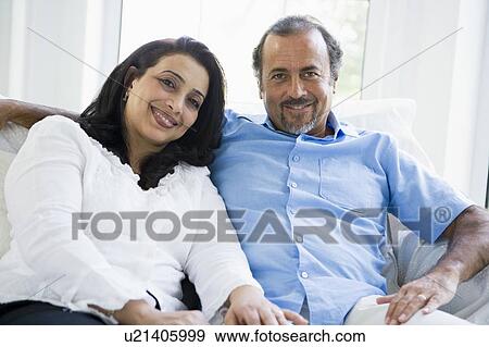 Couple sitting in living room smiling (high key) View Large Photo Image Stock Photo - Couple sitting in living room smiling (high key). Fotosearch
