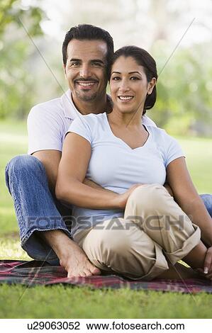 Couple sitting outdoors in park smiling (selective focus) View Large Photo Image Stock Image - Couple sitting outdoors in park smiling (selective focus). Fotosearch