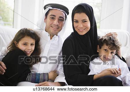 Picture - Family sitting in living room smiling (high key/selective focus). Fotosearch