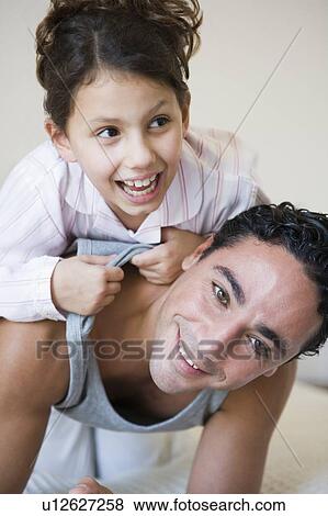 Stock Photo - Man and young girl playing on bed in bedroom smiling (selective focus). Fotosearch
