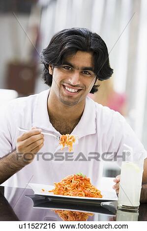 Man at restaurant eating spaghetti and smiling (selective focus) View Large Photo Image Stock Photograph - Man at restaurant eating spaghetti and smiling (selective focus). Fotosearch