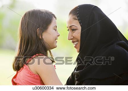 Picture - Mother and daughter outdoors in park embracing and smiling (selective focus). Fotosearch