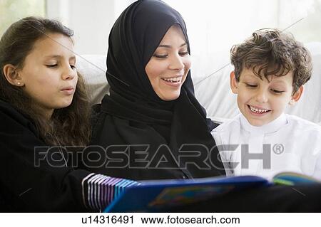Mother and two young children in living room reading book and smiling (high key/selective focus) View Large Photo Image Stock Image - Mother and two young children in living room reading book and smiling (high key/selective focus). Fotosearch
