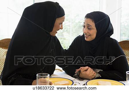 Two women sitting at dinner table smiling (high key) View Large Photo Image Stock Image - Two women sitting at dinner table smiling (high key). Fotosearch