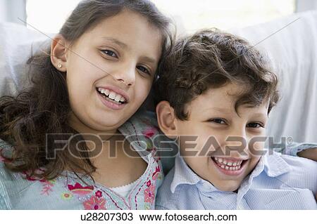 Stock Image - Two young children in living room smiling (high key). Fotosearch