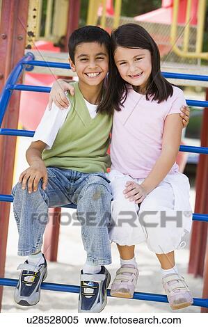 Stock Photography - Two young children sitting on playground structure smiling (selective focus). Fotosearch