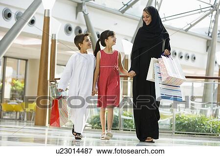 Woman and two young children walking in mall smiling (selective focus) View Large Photo Image Stock Photo - Woman and two young children walking in mall smiling (selective focus). Fotosearch