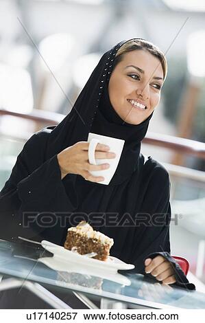 Stock Photo - Woman at restaurant eating dessert and smiling (selective focus). Fotosearch
