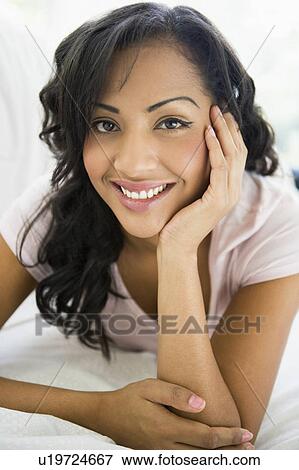 Stock Photo - Woman in living room smiling (high key/selective focus). Fotosearch