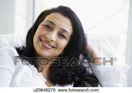 Woman sitting in living room smiling (high key) View Large Photo Image Stock Image - Woman sitting in living room smiling (high key). Fotosearch
