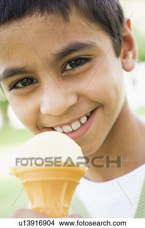 Young boy outdoors eating ice cream and smiling (selective focus) View Large Photo Image Picture - Young boy outdoors eating ice cream and smiling (selective focus). Fotosearch