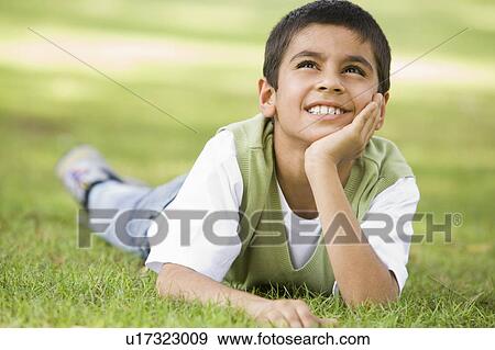Young boy outdoors lying in grass and smiling (selective focus) View Large Photo Image Stock Photo - Young boy outdoors lying in grass and smiling (selective focus). Fotosearch