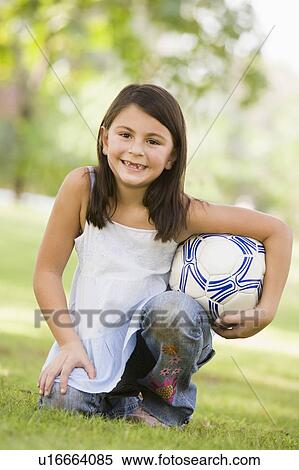 Young girl outdoors at park holding ball and smiling (selective focus) View Large Photo Image Stock Photography - Young girl outdoors at park holding ball and smiling (selective focus). Fotosearch