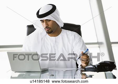 Businessman in office with laptop working (high key/selective focus) View Large Photo Image Stock Photo - Businessman in office with laptop working (high key/selective focus). Fotosearch