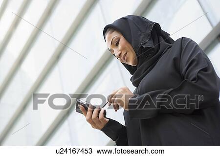 Businesswoman outdoors by building using personal digital assistant and smiling (selective focus) View Large Photo Image Stock Image - Businesswoman outdoors by building using personal digital assistant and smiling (selective focus). Fotosearch
