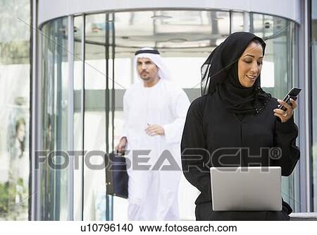 Businesswoman sitting outdoors by building with laptop holding cellular phone with businessman running in background (selective focus) View Large Photo Image Stock Image - Businesswoman sitting outdoors by building with laptop holding cellular phone with businessman running in background (selective focus). Fotosearch
