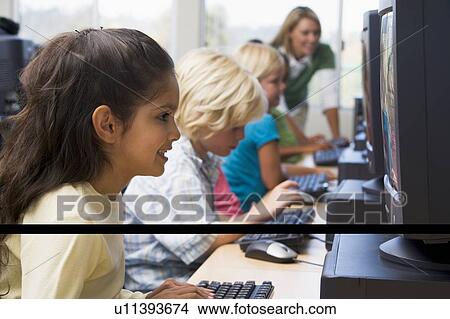 Children at computer terminals with teacher in background (depth of field/high key) View Large Photo Image Picture - Children at computer terminals with teacher in background (depth of field/high key). Fotosearch