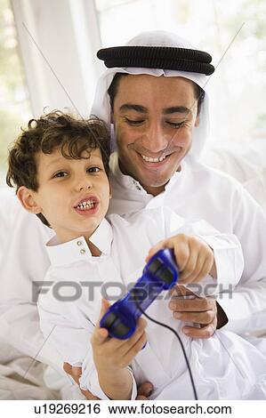 Father and son in living room playing video games and smiling (high key/selective focus) View Large Photo Image Stock Photograph - Father and son in living room playing video games and smiling (high key/selective focus). Fotosearch