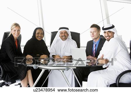 Picture - Five businesspeople in office with laptop smiling (high key/selective focus). Fotosearch