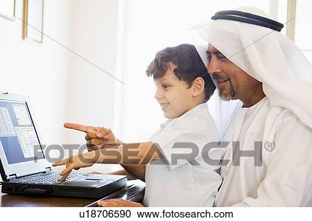 Man and young boy in office with laptop pointing and smiling (high key/selective focus) View Large Photo Image Stock Image - Man and young boy in office with laptop pointing and smiling (high key/selective focus). Fotosearch