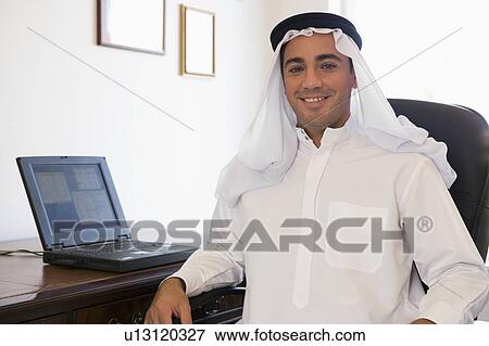 Stock Photo - Man in office with laptop smiling (high key/selective focus). Fotosearch