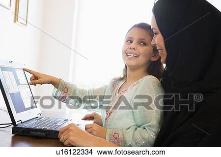 Mother and daughter in office with laptop pointing and smiling (high key/selective focus) View Large Photo Image Picture - Mother and daughter in office with laptop pointing and smiling (high key/selective focus). Fotosearch