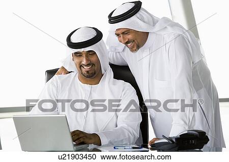 Two businessmen in office with laptop smiling (high key/selective focus) View Large Photo Image Stock Image - Two businessmen in office with laptop smiling (high key/selective focus). Fotosearch