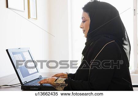 Stock Photography - Woman in office with laptop (high key/selective focus). Fotosearch