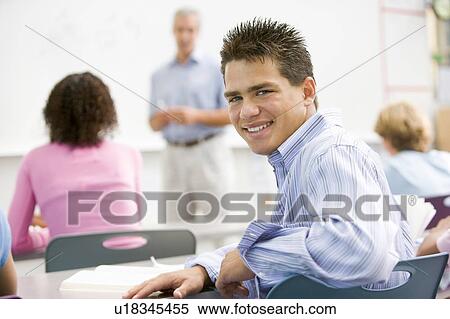 Stock Photography - Male student with other students in classroom. Fotosearch