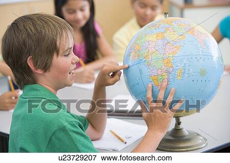 Student in class pointing at a globe (selective focus) View Large Photo Image Stock Photo - Student in class pointing at a globe (selective focus). Fotosearch