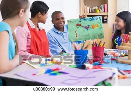 Stock Photo - Student showing teacher and classmates his artwork (selective focus). Fotosearch