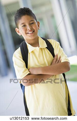 Stock Image - Student standing outside school smiling (selective focus). Fotosearch