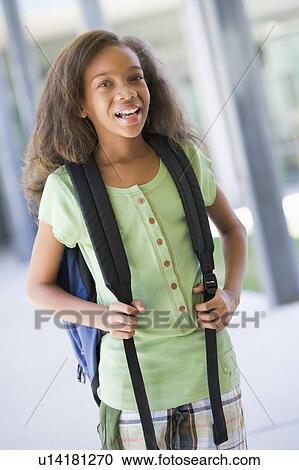 Stock Image - Student standing outside school smiling (selective focus). Fotosearch