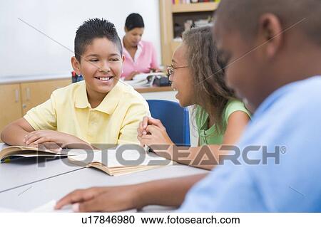 Students in class reading with teacher in background (selective focus) View Large Photo Image Stock Image - Students in class reading with teacher in background (selective focus). Fotosearch