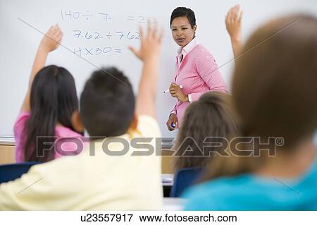 Students in class volunteering for teacher at front board (selective focus) View Large Photo Image Stock Photo - Students in class volunteering for teacher at front board (selective focus). Fotosearch