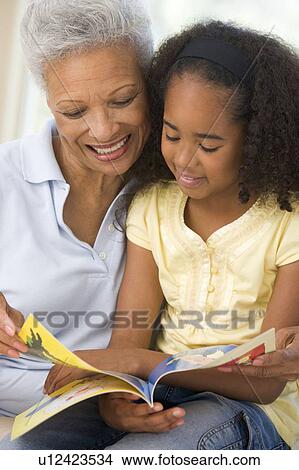 Picture - Grandmother and granddaughter reading and smiling. Fotosearch