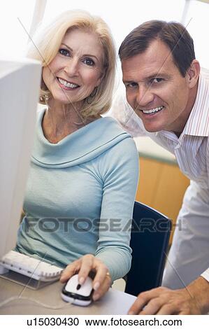 Stock Image - Man and woman at computer smiling (high key). Fotosearch