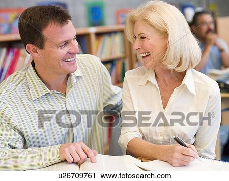 Stock Image - Man and woman in library laughing (selective focus). Fotosearch