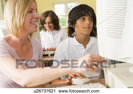 Student and teacher at computer terminal with student in background (selective focus) View Large Photo Image Stock Image - Student and teacher at computer terminal with student in background (selective focus). Fotosearch