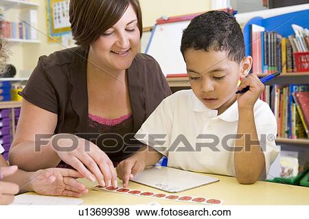 Stock Photo - Student in class with teacher learning numbers. Fotosearch