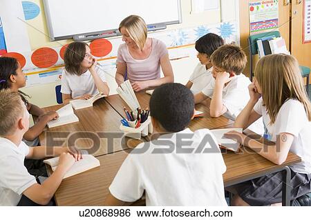 Stock Photograph - Students in class reading books with teacher. Fotosearch