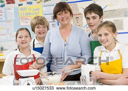 Stock Image - Students preparing ingredients in cooking class with teacher. Fotosearch