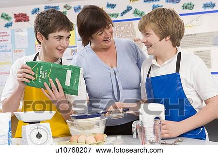Stock Photo - Students preparing ingredients in cooking class with teacher. Fotosearch