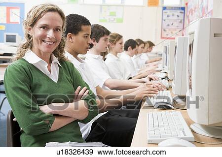 Stock Photo - Students working on computer workstations with teacher. Fotosearch