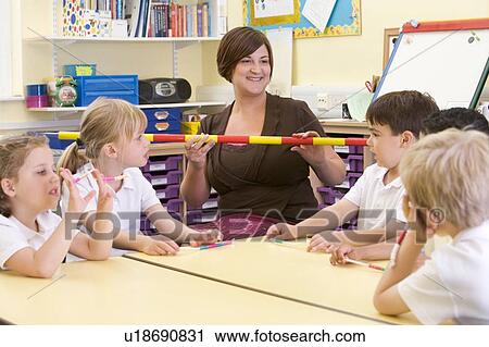 Stock Image - Teacher and students in math class with measuring stick. Fotosearch