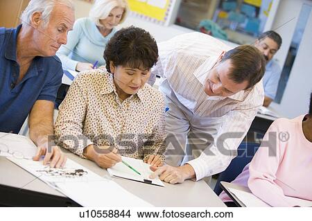 Picture - Teacher in class helping adult students (selective focus). Fotosearch