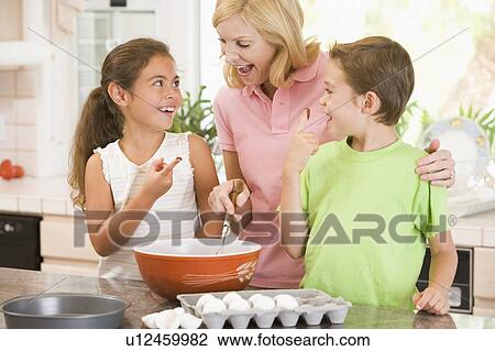 Woman and two children in kitchen baking and smiling View Large Photo Image Stock Image - Woman and two children in kitchen baking and smiling. Fotosearch