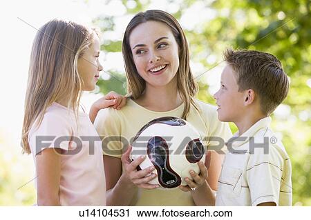 Woman and two young children outdoors holding volleyball and smiling View Large Photo Image Stock Image - Woman and two young children outdoors holding volleyball and smiling. Fotosearch