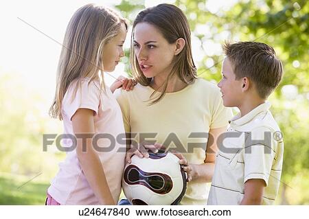 Woman and two young children outdoors holding volleyball and smiling View Large Photo Image Stock Image - Woman and two young children outdoors holding volleyball and smiling. Fotosearch